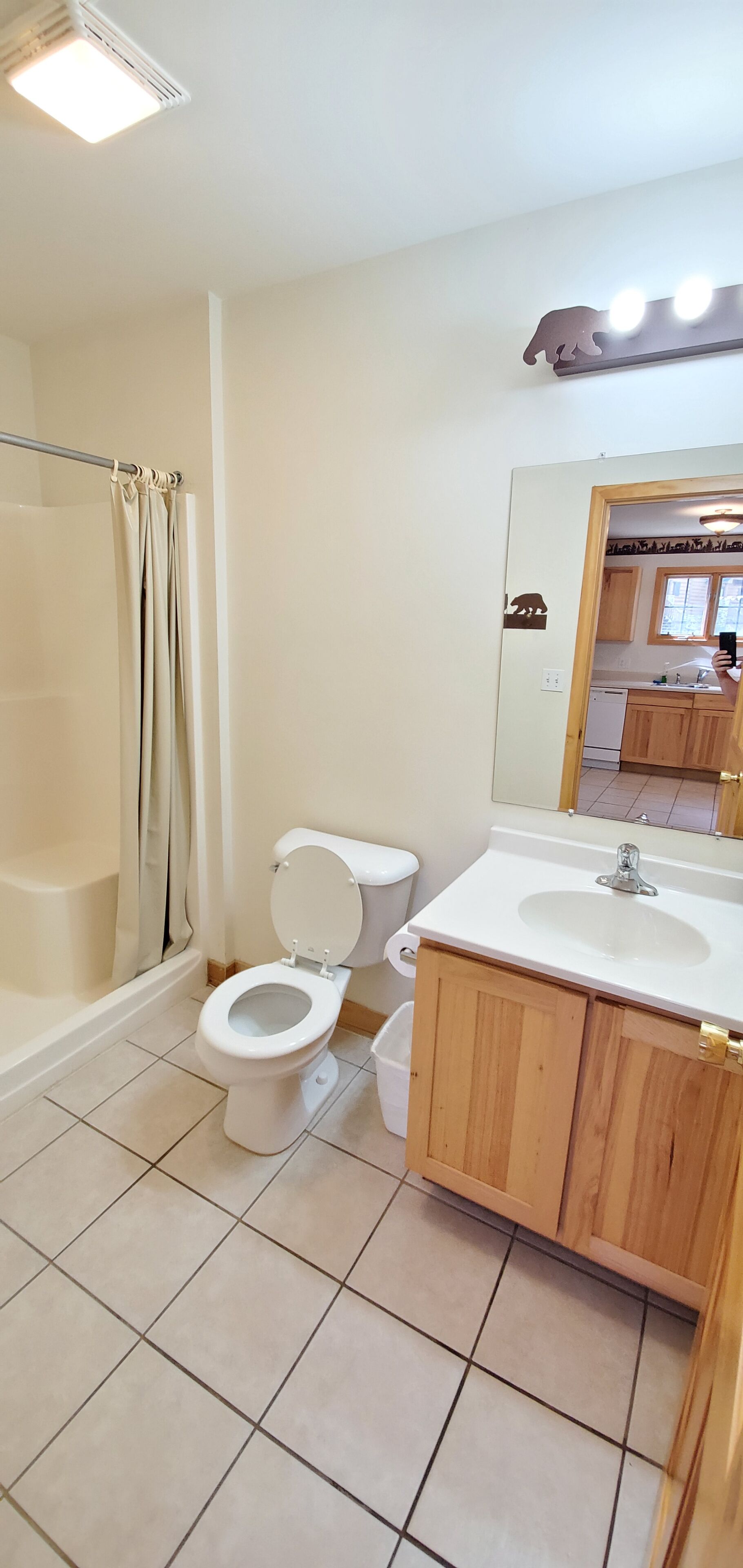 A bathroom with a toilet, sink, wooden cabinets, a shower curtain, and a bathtub.