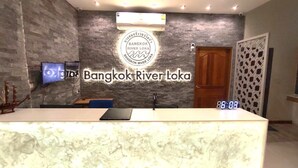 A reception area with a marble counter, a digital clock, and a wall-mounted TV.