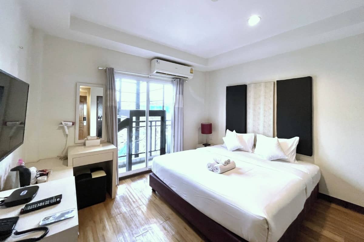 Une chambre d’hôtel équipée d’un lit, d’un bureau avec un ordinateur, d’une télévision et d’un appareil de climatisation.