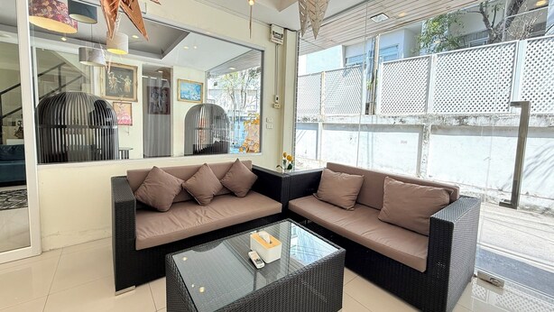 A modern living room with a sectional sofa, a glass coffee table, and a large window with a view of the street.