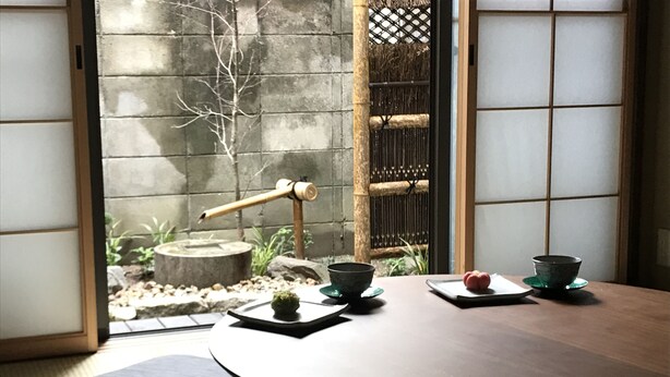 A traditional Japanese room with tatami flooring, a low table with a bowl and chopsticks, and a view of a garden through a shoji screen. - Shounsai (Kyoto)