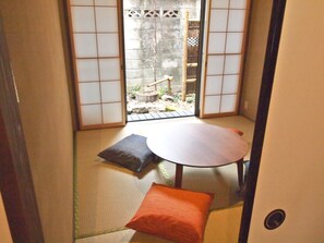 Une pièce de style japonais traditionnel, avec un sol recouvert de tatamis, une table basse et des coussins.