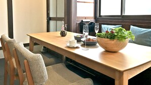 A wooden dining table with a bowl of salad, a wine glass, and a decorative item. - Shounsai (Kyoto)