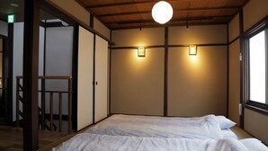 A traditional Japanese-style room with tatami flooring, a low bed, sliding doors, and a wooden ceiling. - Shounsai (Kyoto)