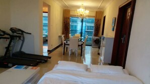 A hotel room with a bed, a treadmill, a desk, and a dining area. - Henda Venice Hotel (Nantong)