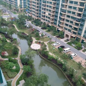 Un edificio residencial de gran altura con un área ajardinada que incluye un jardín circular y una fuente de agua.