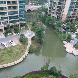 Zona residencial a orillas del río con edificios modernos, un puente peatonal y un parque pequeño con bancos.