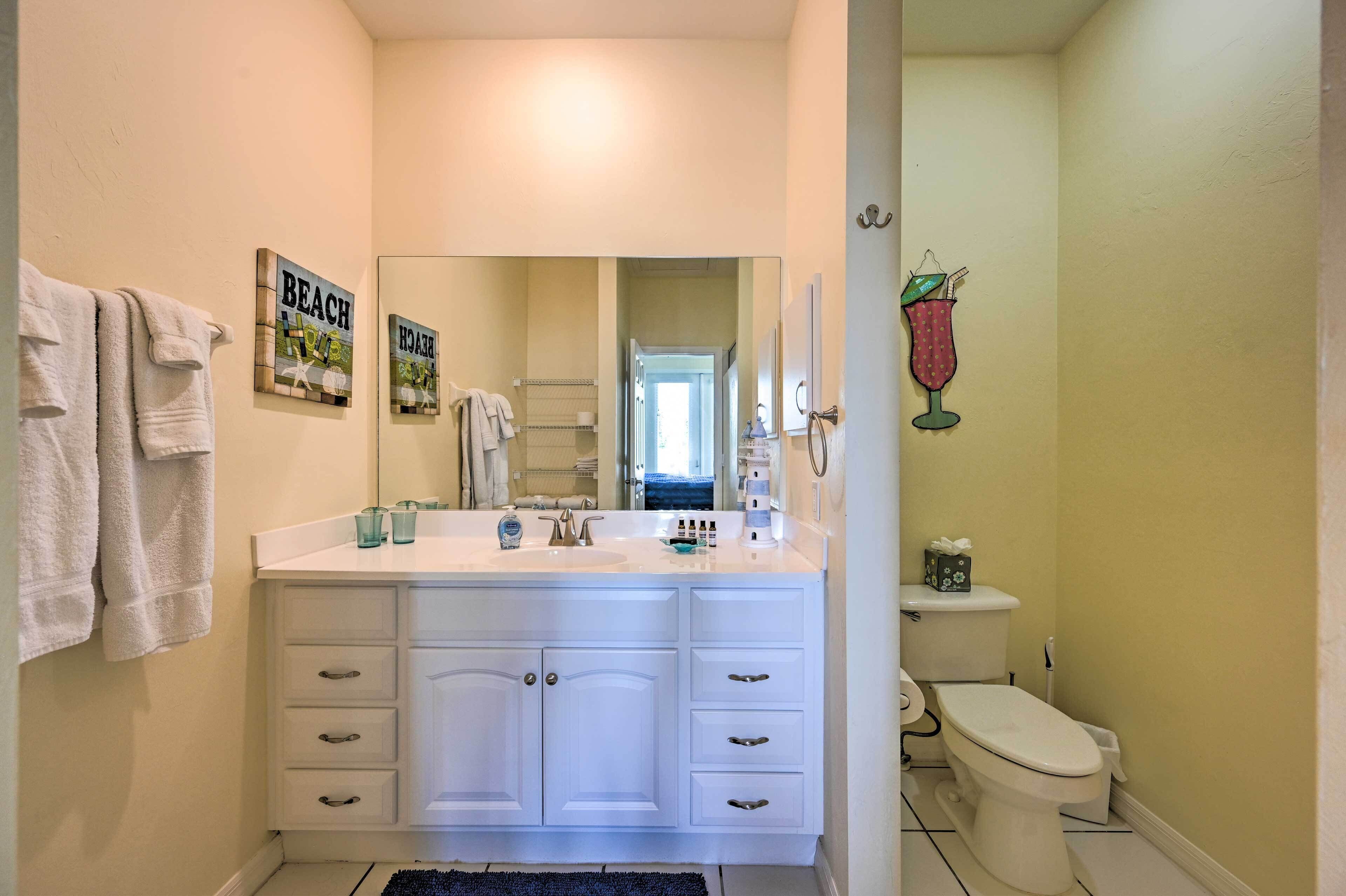 Een badkamer met een wit wastafelmeubel, een spiegel, een toilet en een handdoekhouder.