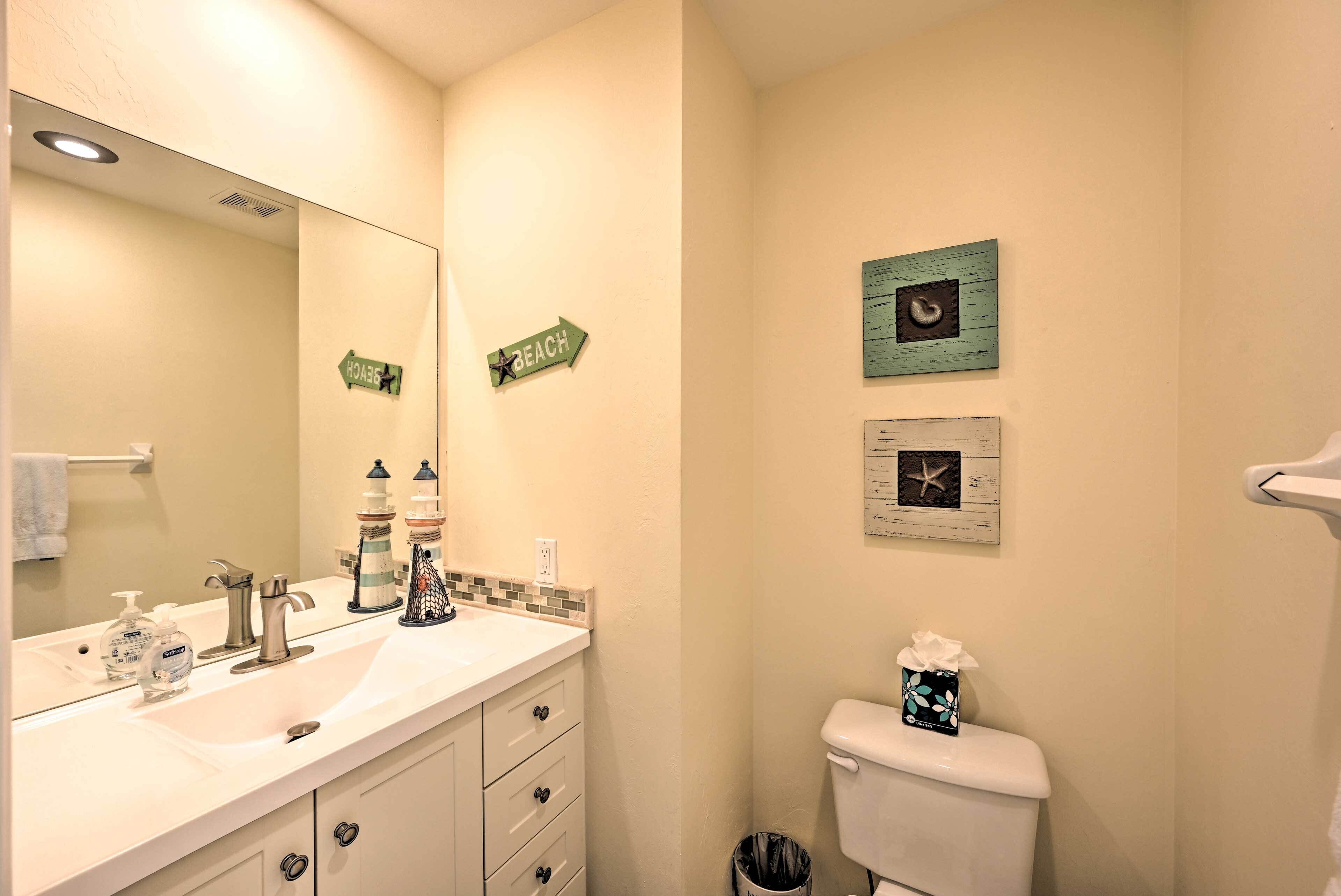 Un bagno con lavandino, specchio, toilette e oggetti decorativi.