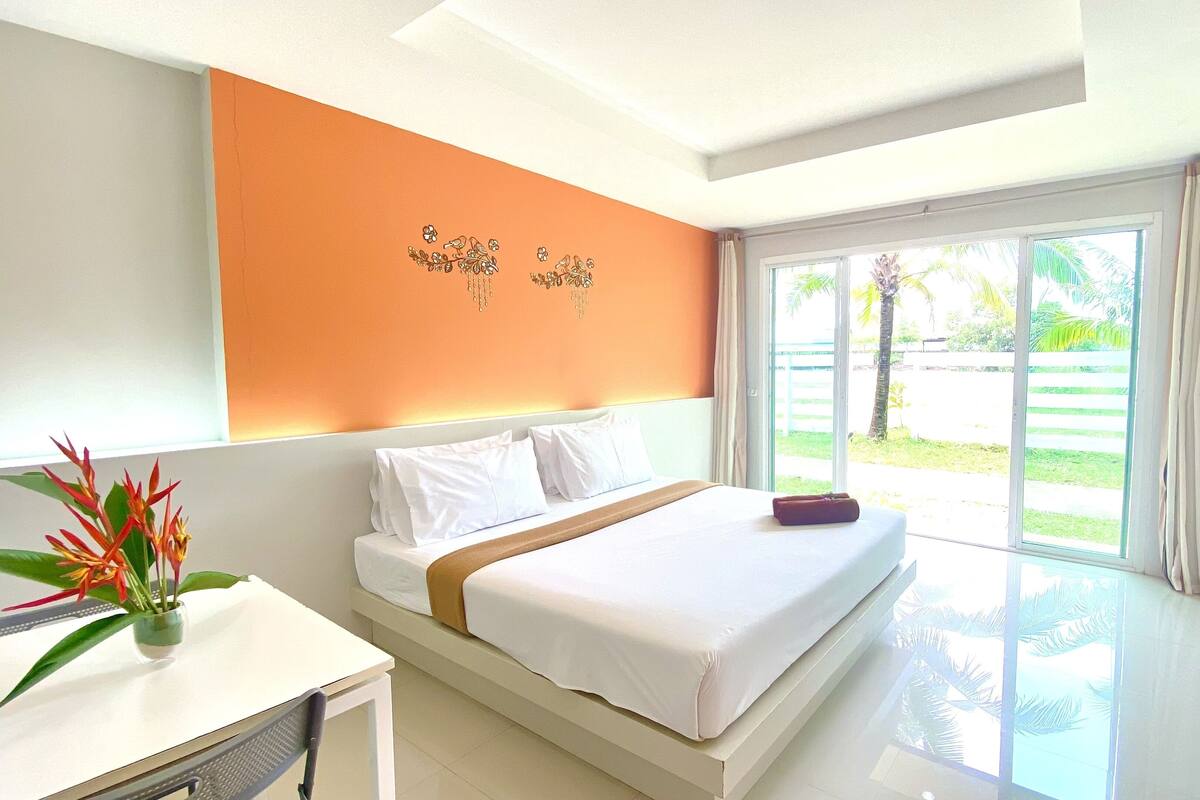 A hotel room with a large bed, a desk with a chair, a TV, and a view of the outdoors.