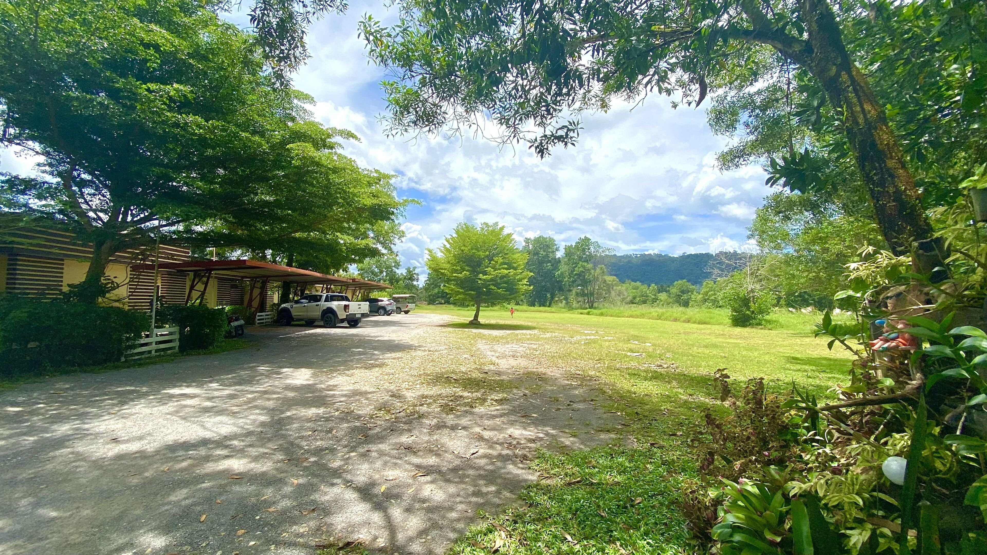 A rural setting with a covered parking area, a white pickup truck, and a bus.