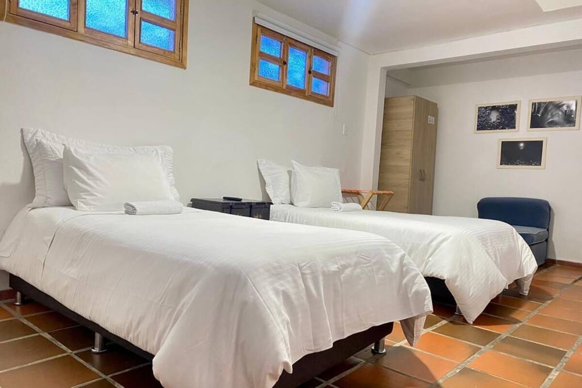 Una habitación con dos camas, una silla y un armario.