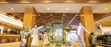 Un hall con columnas de madera, una fuente decorativa y un mostrador de recepción.