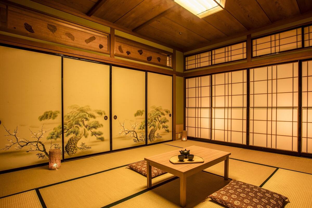 Une pièce de style japonais traditionnel, avec un sol recouvert de tatamis, des paravents en papier de riz (shoji) et une petite table sur laquelle est disposé un service à thé.