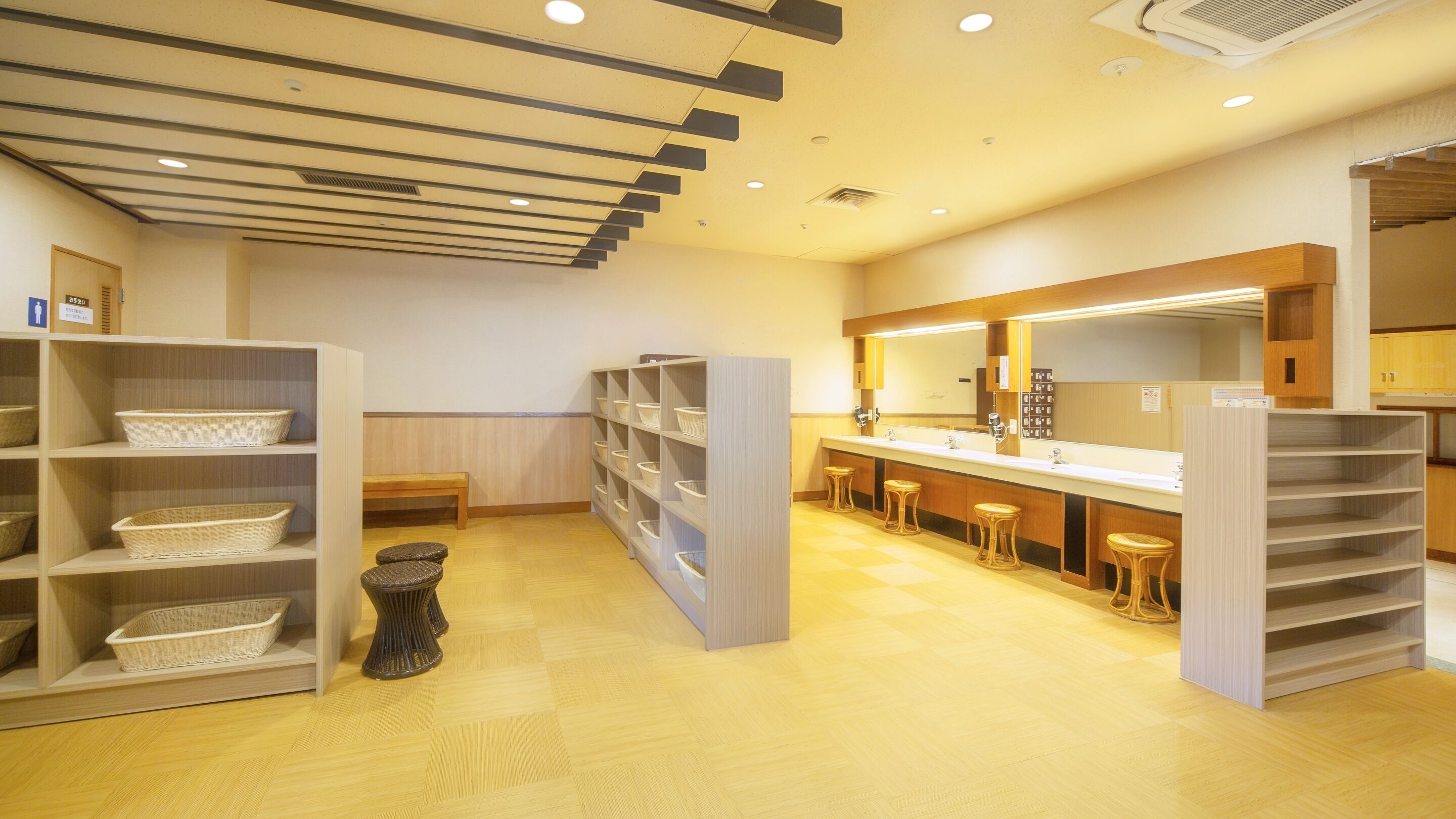 Una habitación de hotel con piso de madera, una larga barra con taburetes y estantes con cestas.