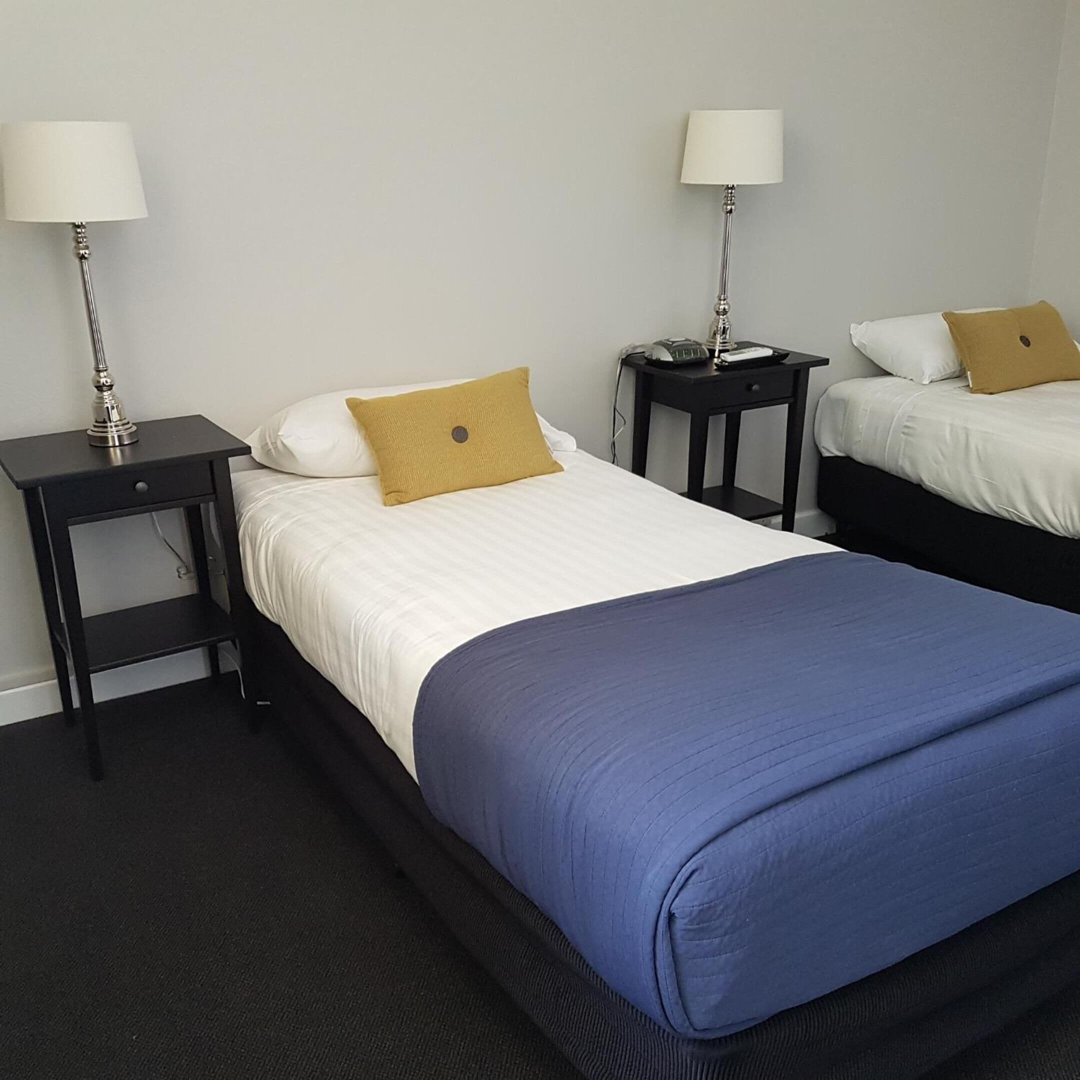 A hotel room with a large bed, two bedside tables, and two lamps.