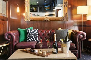 A plush leather sofa with decorative pillows, a bottle of champagne, glasses, and a tray of cheese and crackers on a table.