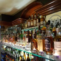 A bar with a variety of liquor bottles and glasses on shelves.
