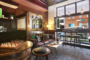 A cozy lounge area with a chessboard, leather sofa, and a large mirror.