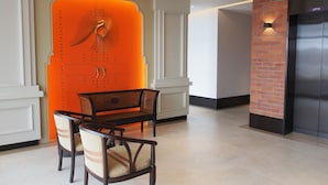 Un interior moderno con comedor que incluye una mesa y sillas, una pared de acento naranja brillante y una pared de ladrillo decorativa.