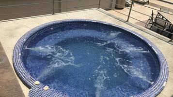 Un jacuzzi con borde de azulejos en una terraza en la azotea.