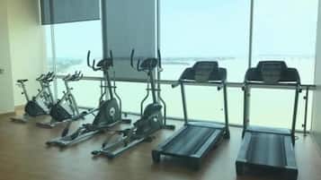 Un gimnasio con bicicletas estáticas, elípticas y cintas de correr, con amplios ventanales que ofrecen vista al mar.