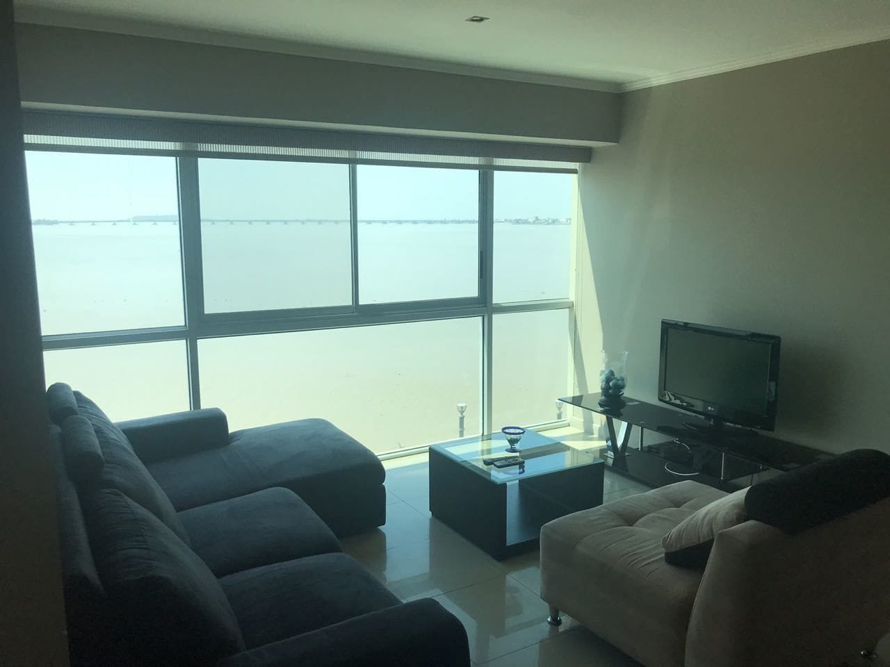 Un saló amb una finestra gran, un sofà, una taula de centre i una televisió.