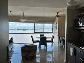 Una cocina moderna con vista al agua, un comedor con mesa y sillas, y un ventilador de techo.