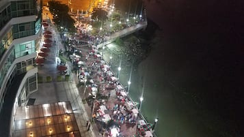 Un paseo a orillas del río con mesas al aire libre y un puente.