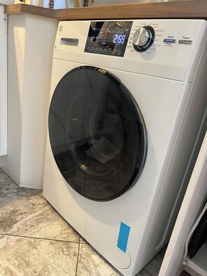 A front-loading washing machine with a digital display, control panel, and a blue tape on the door. - Craftsman Corridor - Free Parking - Fast WIFI - Near UW (Seattle)