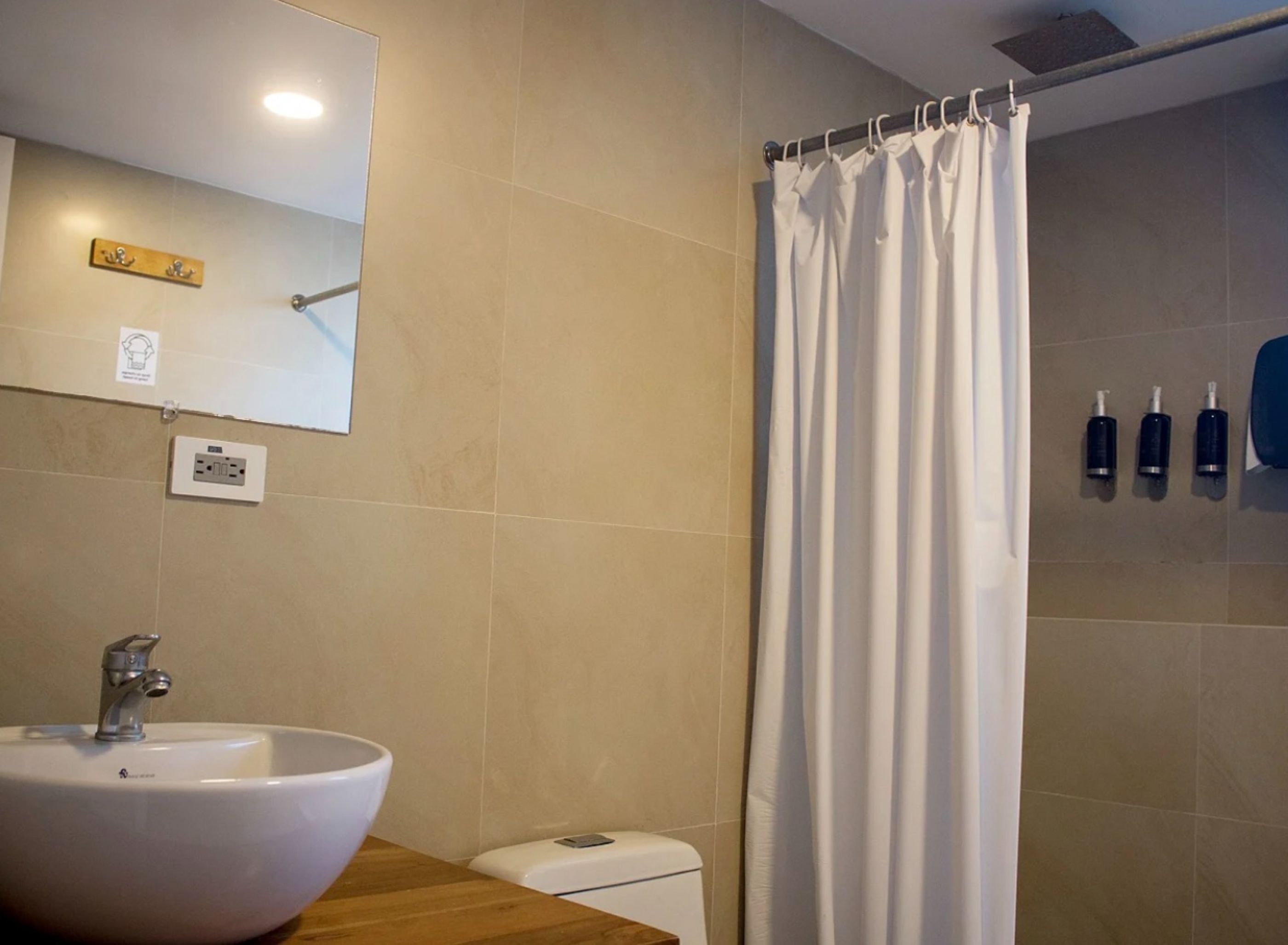 Een badkamer met een witte wastafel, een spiegel, douchegordijn en toilet.