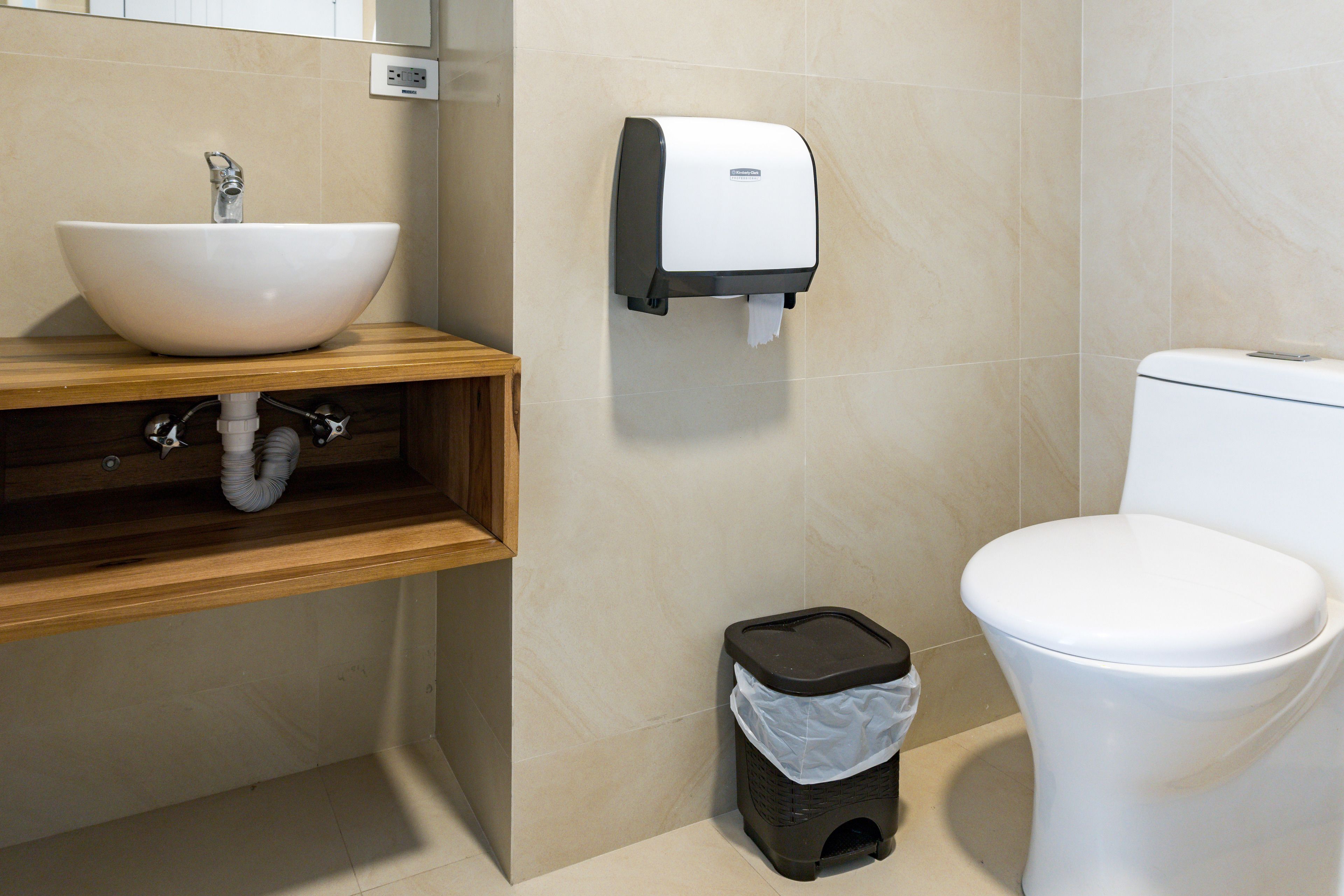 Une salle de bain avec un lavabo blanc, des toilettes et une poubelle.