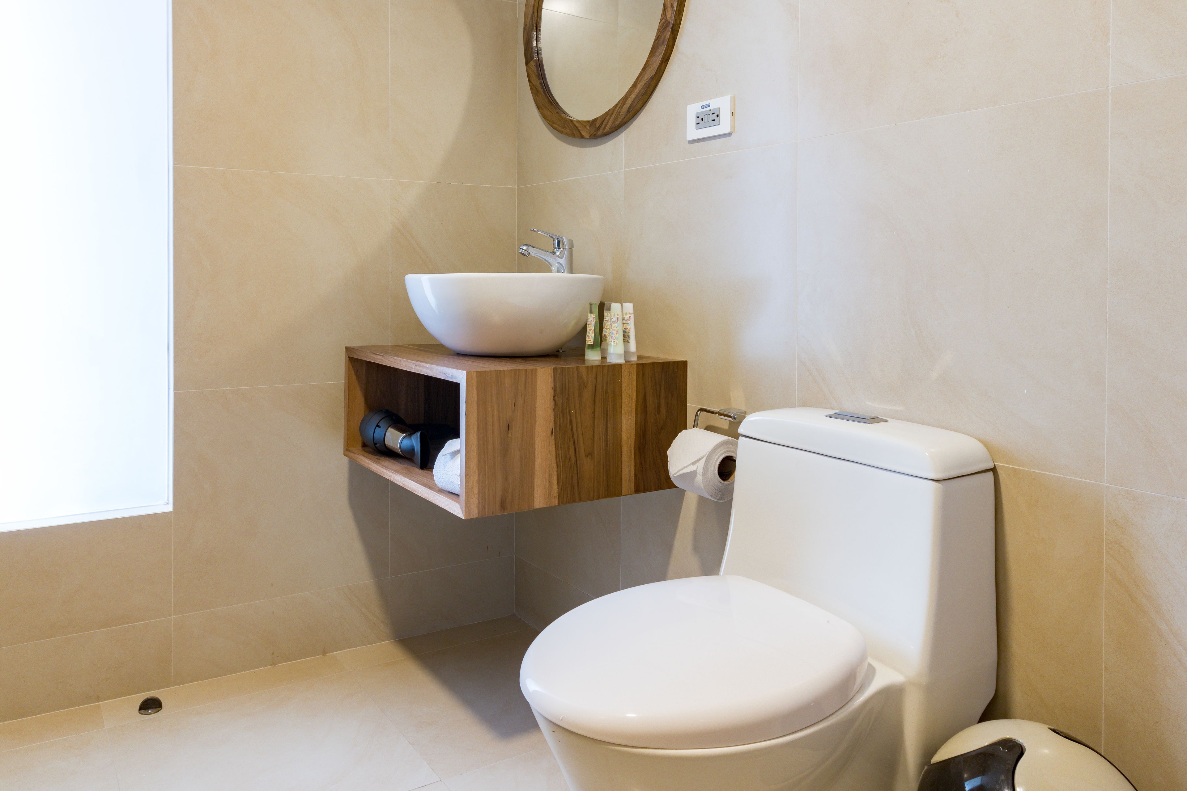 A bathroom with a white toilet, a wooden vanity with a white sink, and a mirror above the sink.