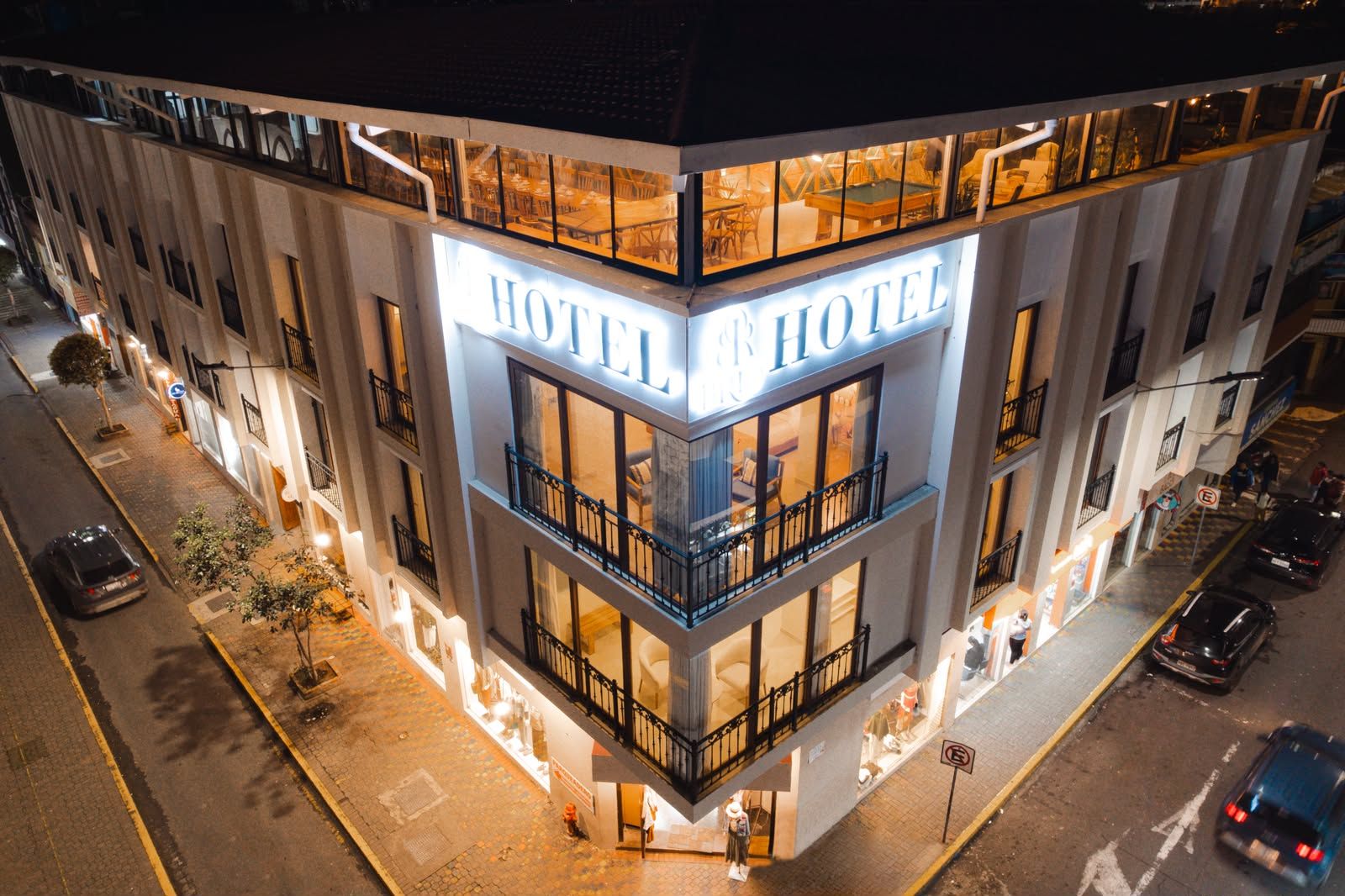 Un hotel con un cartello ben visibile che riporta la scritta 'HOTEL', diversi balconi e posizione all'angolo.