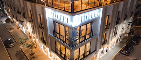 Un hotel con un cartello ben visibile che riporta la scritta 'HOTEL', diversi balconi e posizione all'angolo.