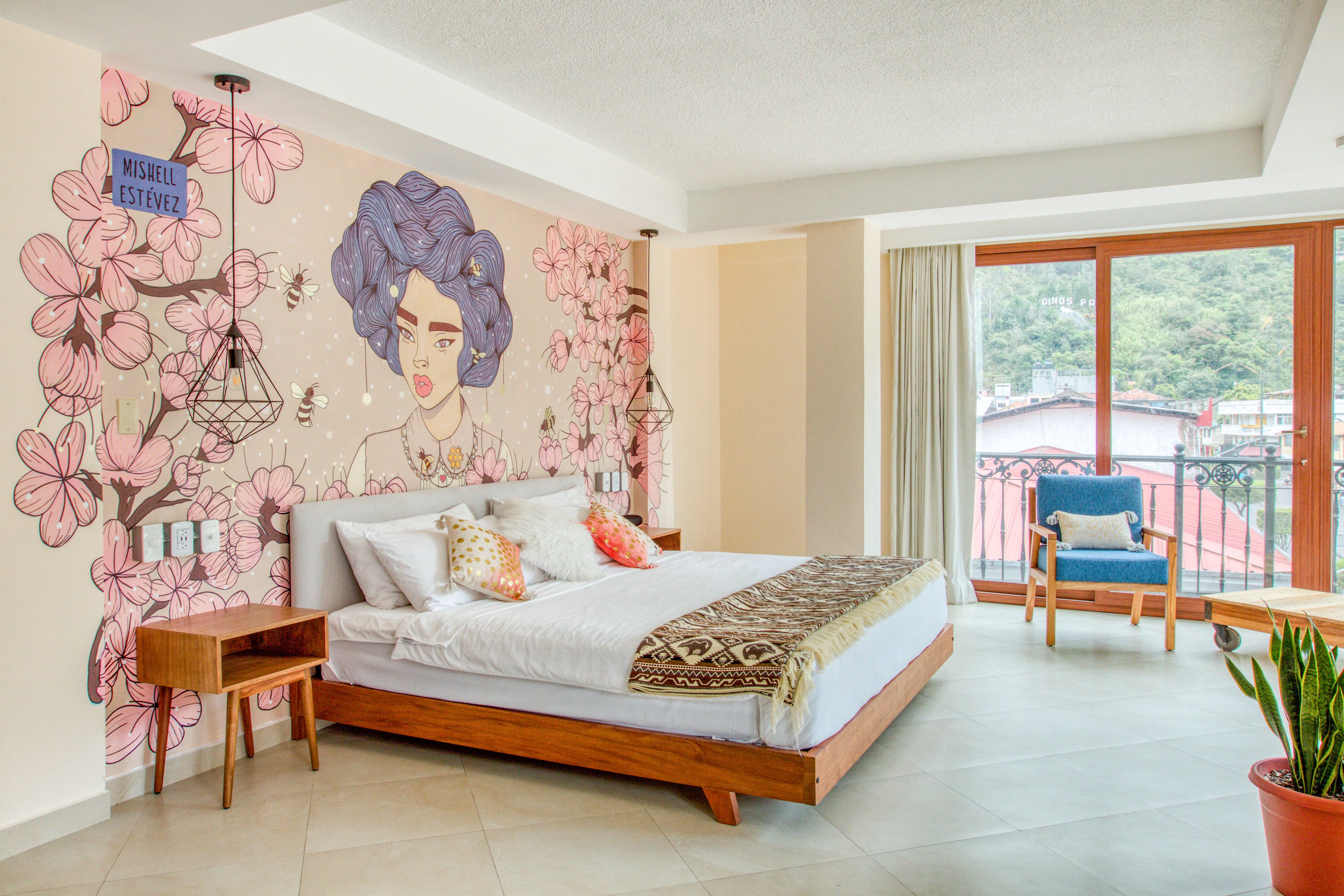 A bedroom with a large bed, a nightstand, a chair, and a balcony with a view.