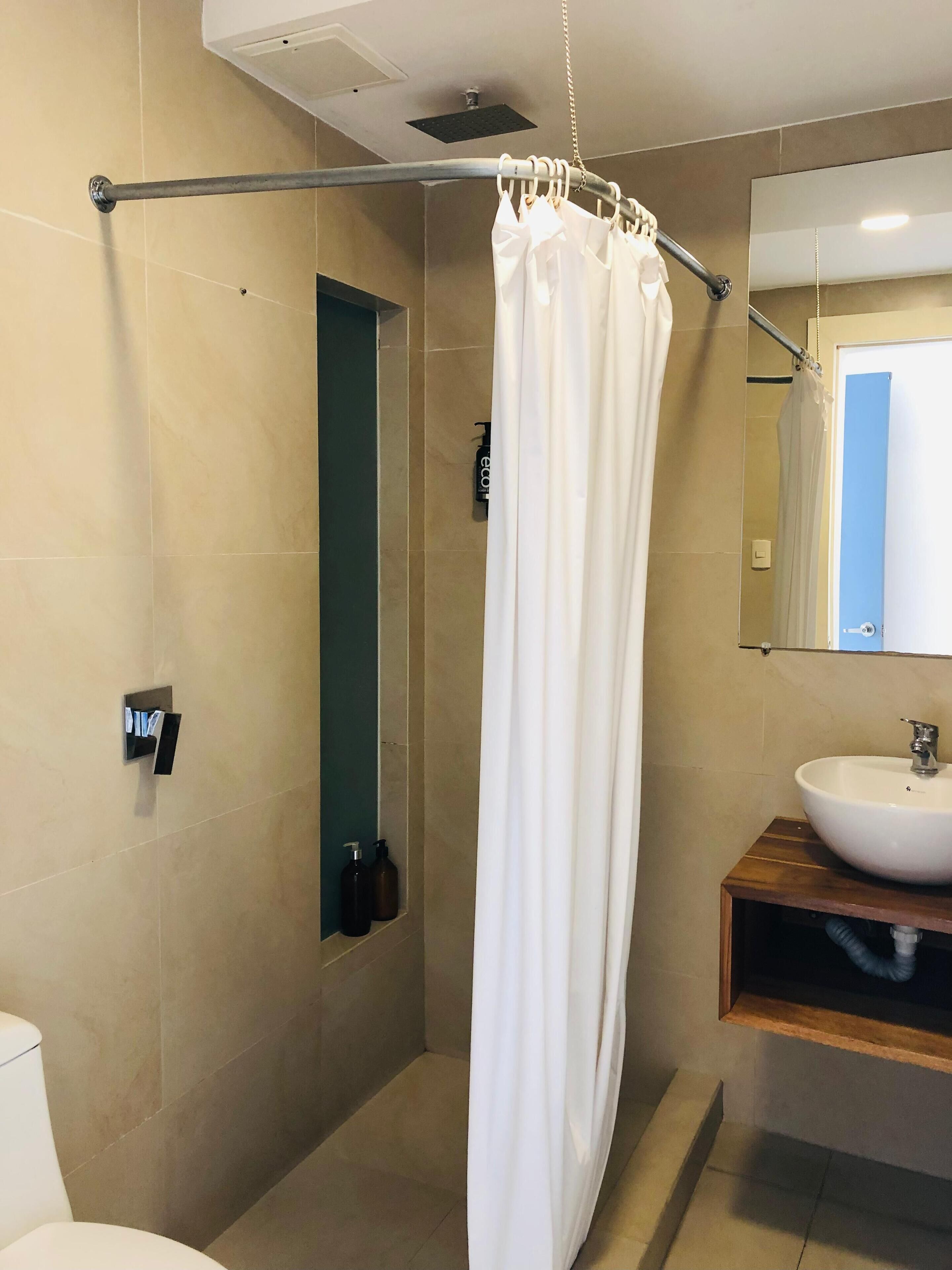 A modern bathroom with a shower curtain, a sink, and a mirror.
