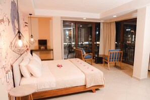 A hotel room with a bed, a desk with a radio, a balcony with chairs, and a city view. - Hotel Brio Centro (Baños de Agua Santa)