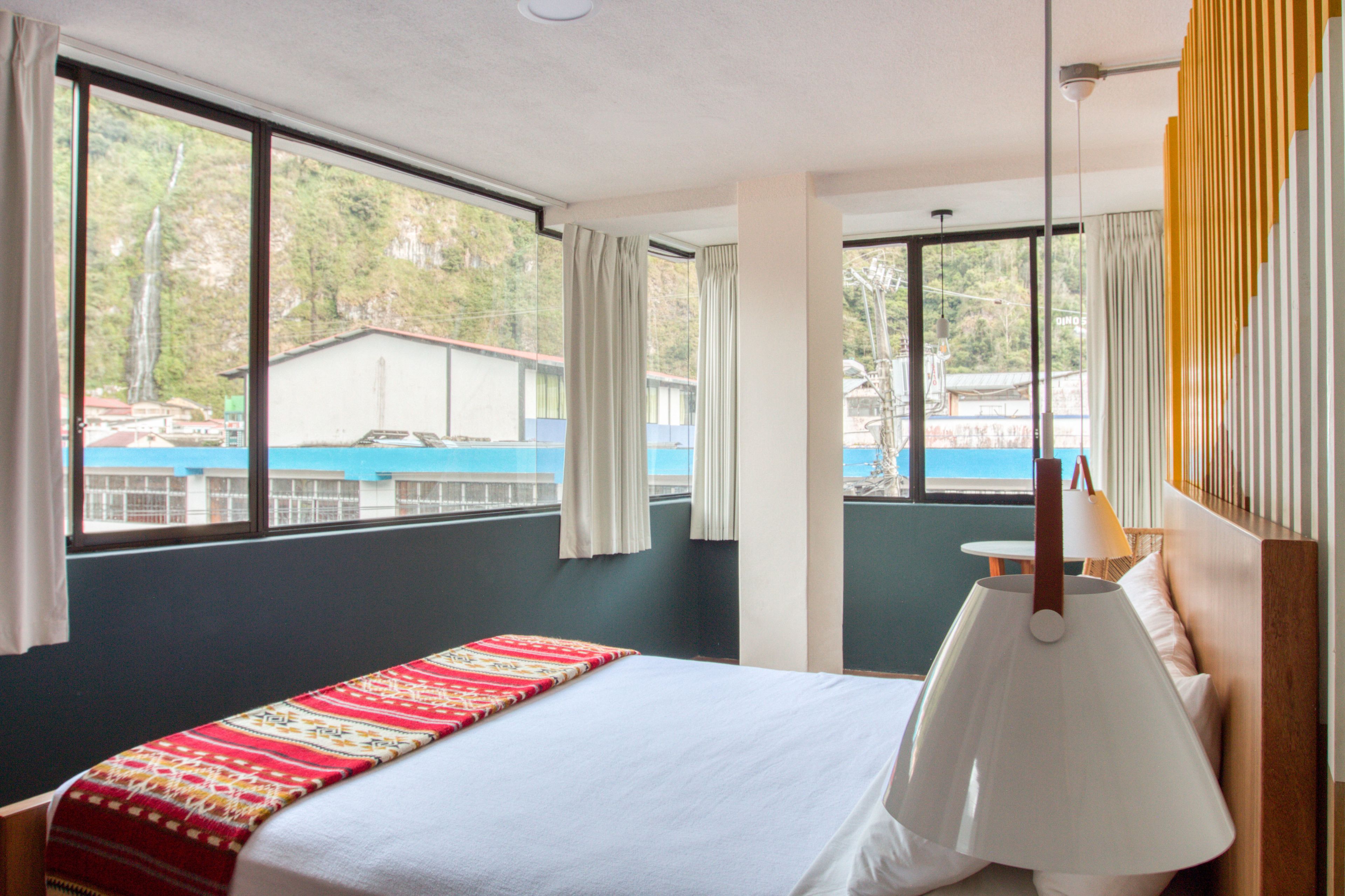 Une chambre d’hôtel avec un lit, une fenêtre avec des rideaux, une vue sur une piscine et une lampe.