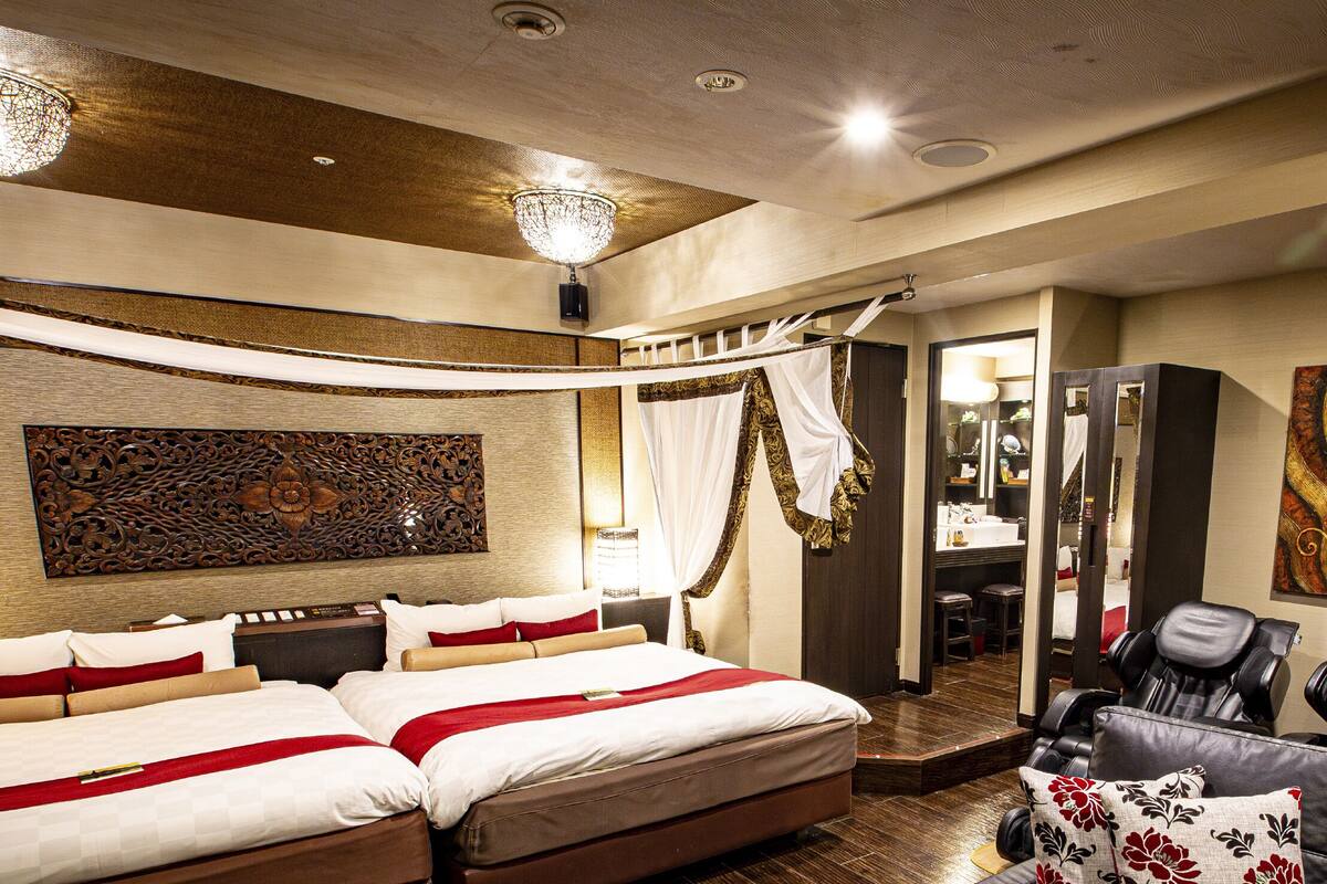 A hotel room with a large bed, a massage chair, and a vanity with a mirror.
