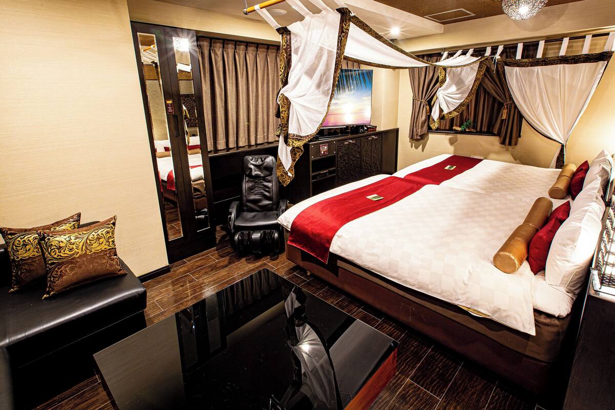 A hotel room with a bed, a desk, a chair, and a mirror.
