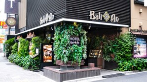 Un hotel con un letrero que dice "Bali Hotel" y una gran exhibición de follaje en la entrada.