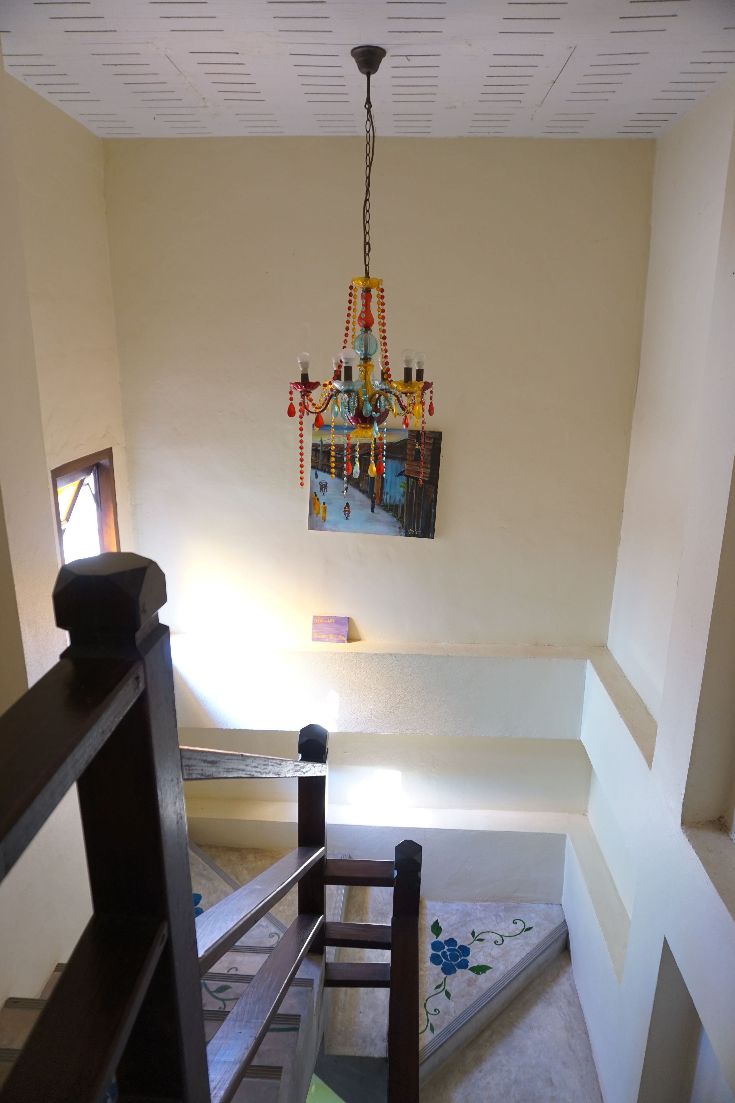 A staircase with a wooden handrail, a hanging dreamcatcher, and a small shelf with a picture frame.