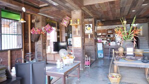 A rustic interior with wooden beams, a television, a fan, and various decorative items. - Chiangkhanburi (Chiang Khan)