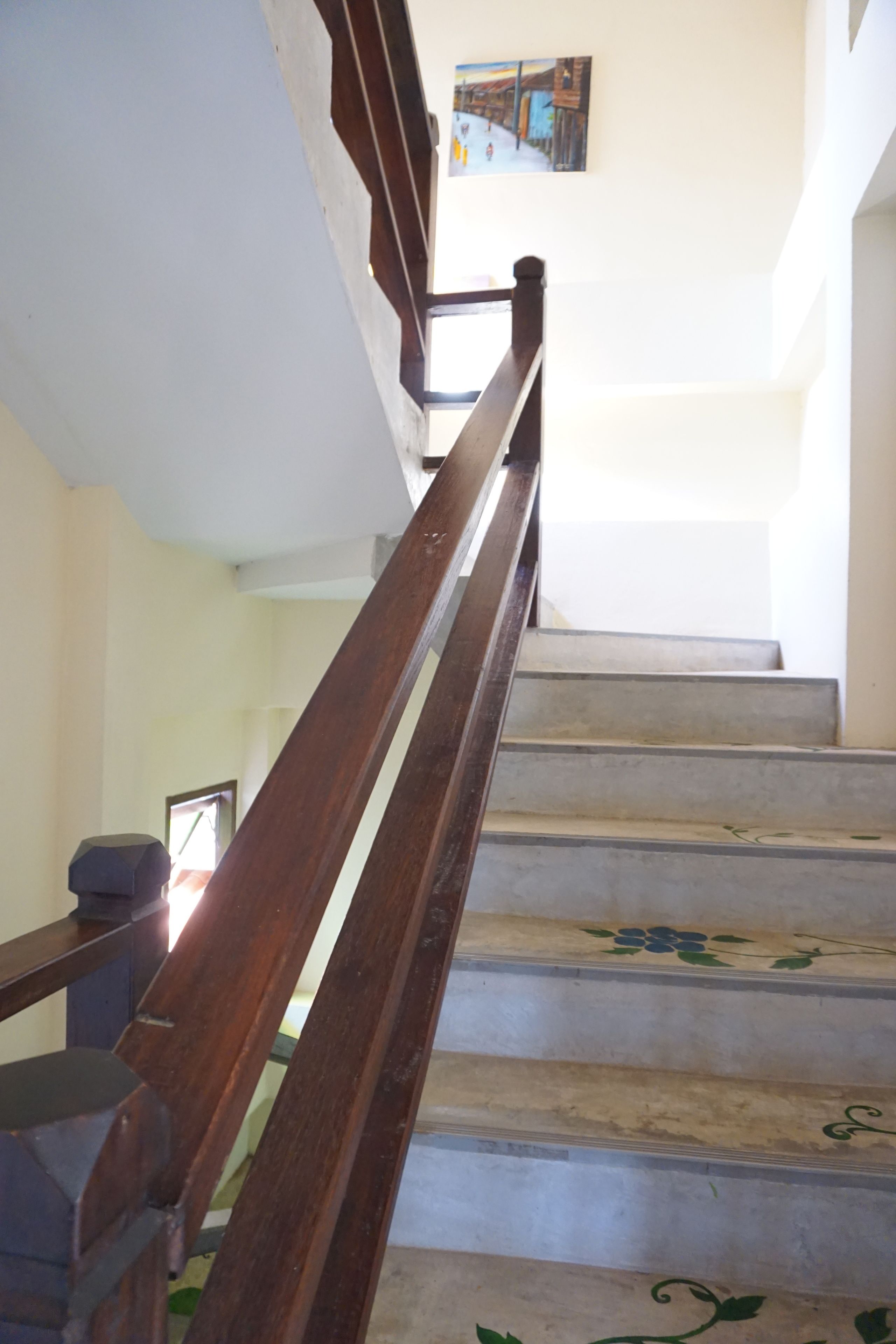 A staircase with wooden handrails and a painting on the wall.