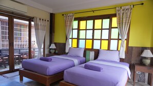 A room with two beds, a wooden floor, a window with curtains, and a view of the outside. - Chiangkhanburi (Chiang Khan)