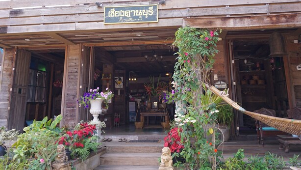 A wooden building with a signboard, steps leading to the entrance, and potted plants. - Chiangkhanburi (Chiang Khan)