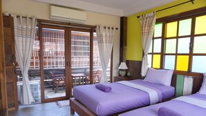 A room with two beds, a sliding glass door to the outside, a small table, and a chair. - Chiangkhanburi (Chiang Khan)