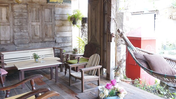 A wooden outdoor seating area with benches and chairs, a hanging light fixture, and a hammock. - Chiangkhanburi (Chiang Khan)