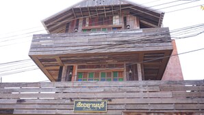 A multi-story wooden building with a balcony and a sign in a foreign script. - Chiangkhanburi (Chiang Khan)